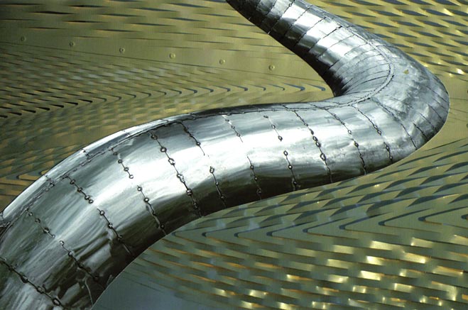 Sinuous metal snake-like form crossing over zig-zag metal background