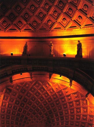 Orange and yellow light on coffered dome interior with balustrade bearing classical statues