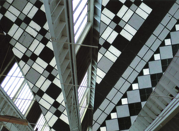 Vertical stripes of checkered tiles with parallel beams and skylights of a factory ceiling