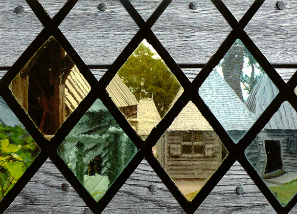 Old colored glass distorts view of reconstructed buildings at historic site