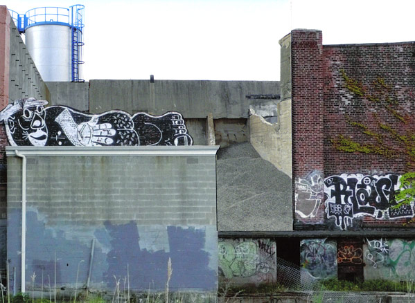 PGraffiti of reclining man on top of a small shed in an industrial setting