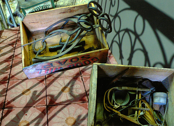 Antique grill work casts shadows around antique tools, Essex Massachusetts Boxes of old hand tools sit on old floral ties covered with loopy shadows